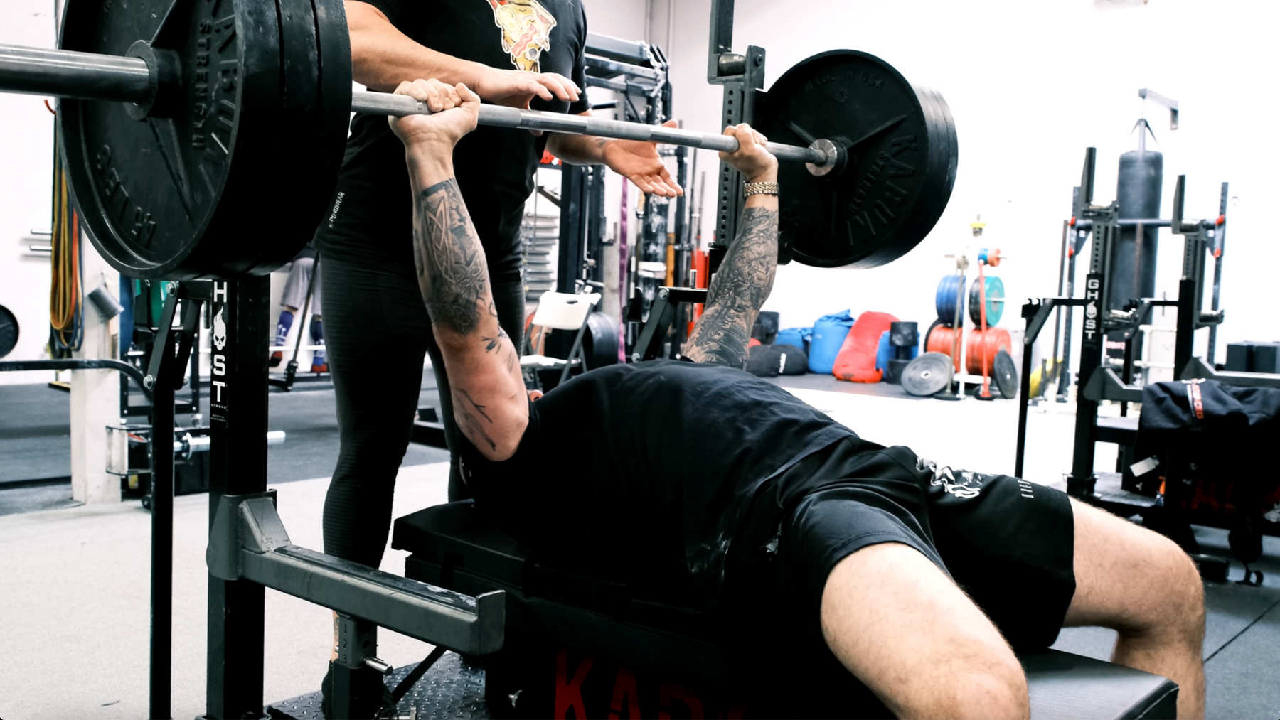 Athlete holding a loaded barbell at the top of a bench press while lying on The Launch Pad®.