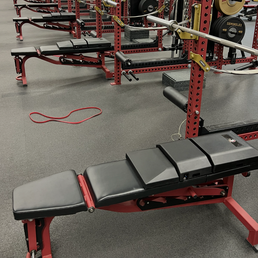 Close side view of three benches fitted with custom-branded versions of The Launch Pad® inside red power racks.
