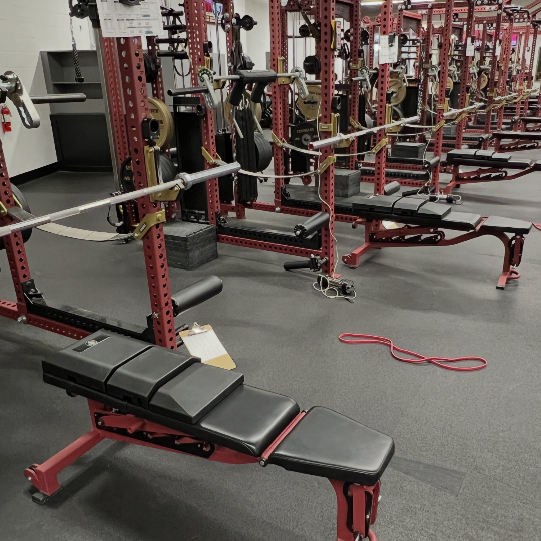 Side angle of three benches equipped with Florida State University custom Launch Pads™ in a collegiate training facility.