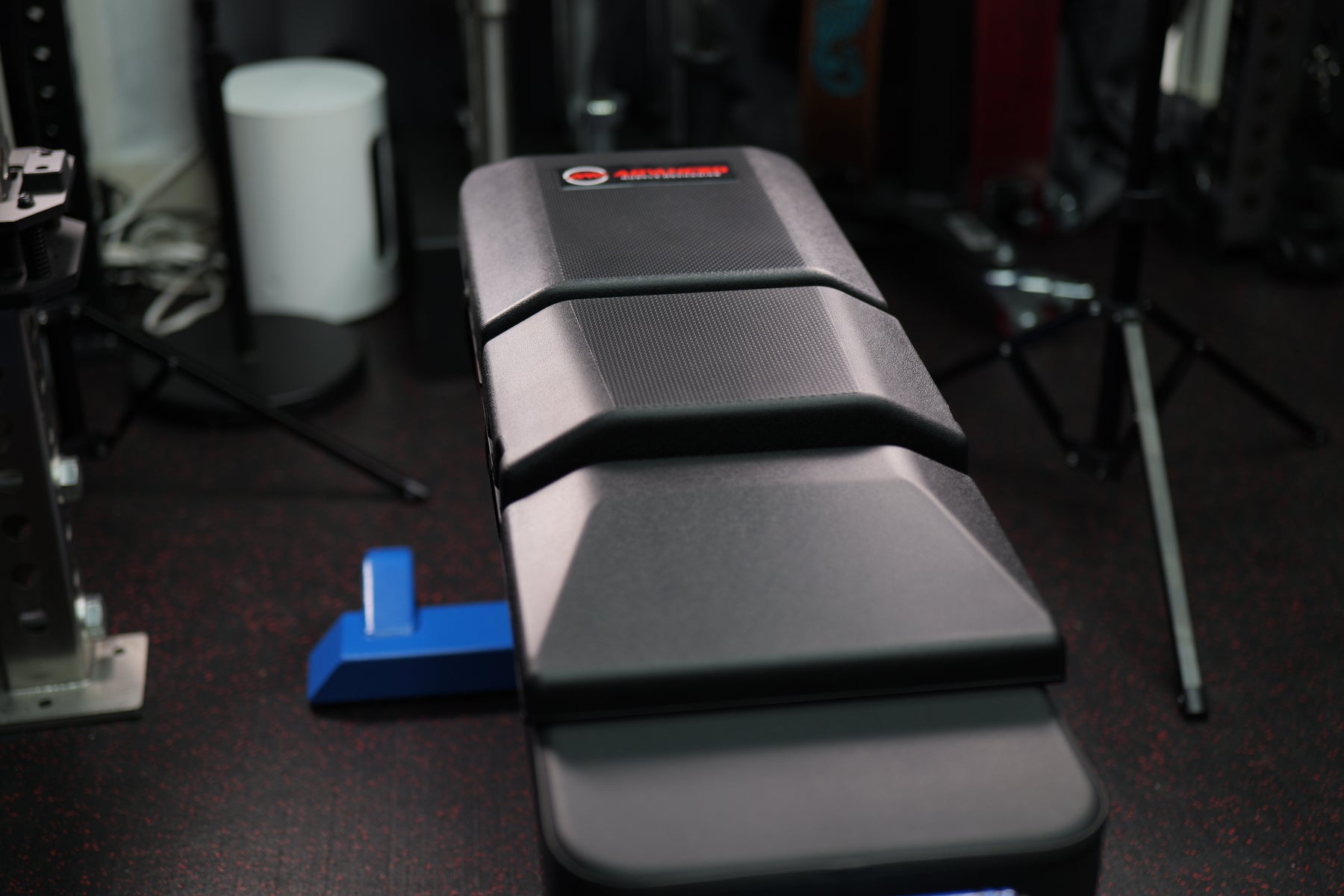 Front view of The Launch Pad® Gen II centered on a flat bench beneath a barbell rack.