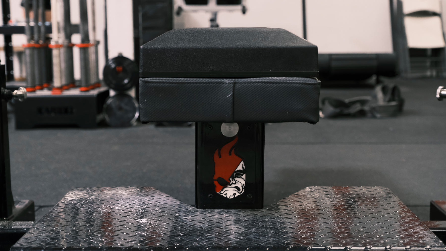 Rear close-up of The Launch Pad® attached to a black flat bench with the strap slots visible.