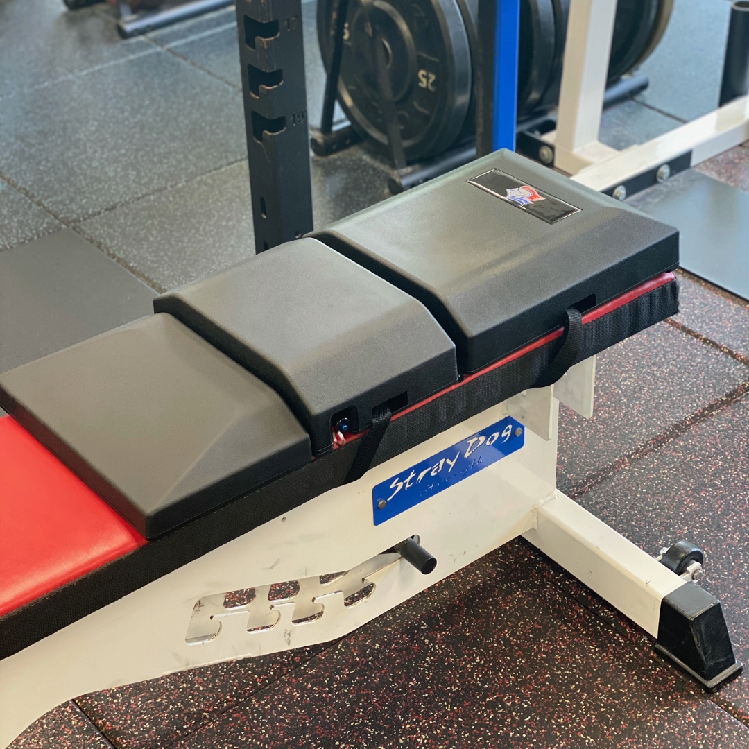 Angled close-up of a custom-branded version of The Launch Pad® on a red bench with the straps visible.