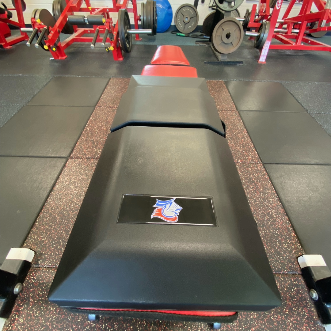Front-to-back view of St. Frances Knights custom Launch Pad™ attached to a flat bench in a weight room, designed for optimal bench press positioning.