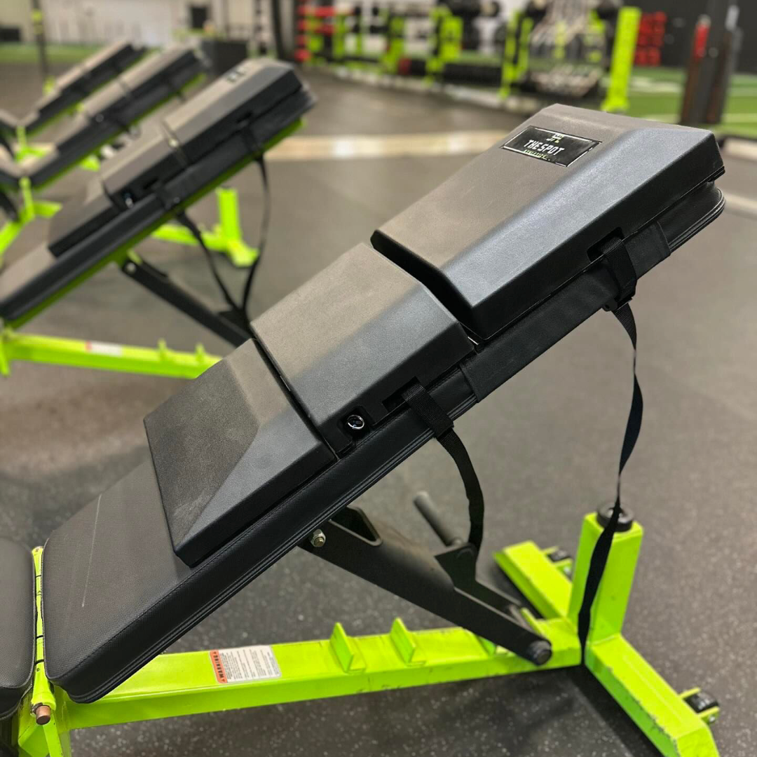 Close-up side angle of four benches outfitted with The Spot Athletics custom Launch Pads™ in a professional training facility.
