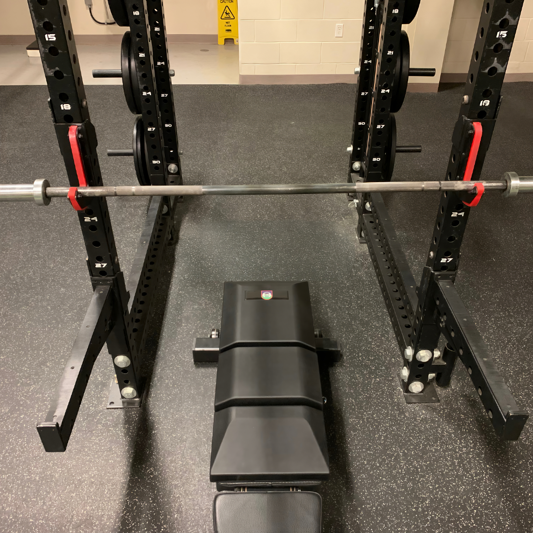 Overhead view of USAF TACP custom Launch Pad™ mounted on a bench in a black power rack, used for tactical strength training.