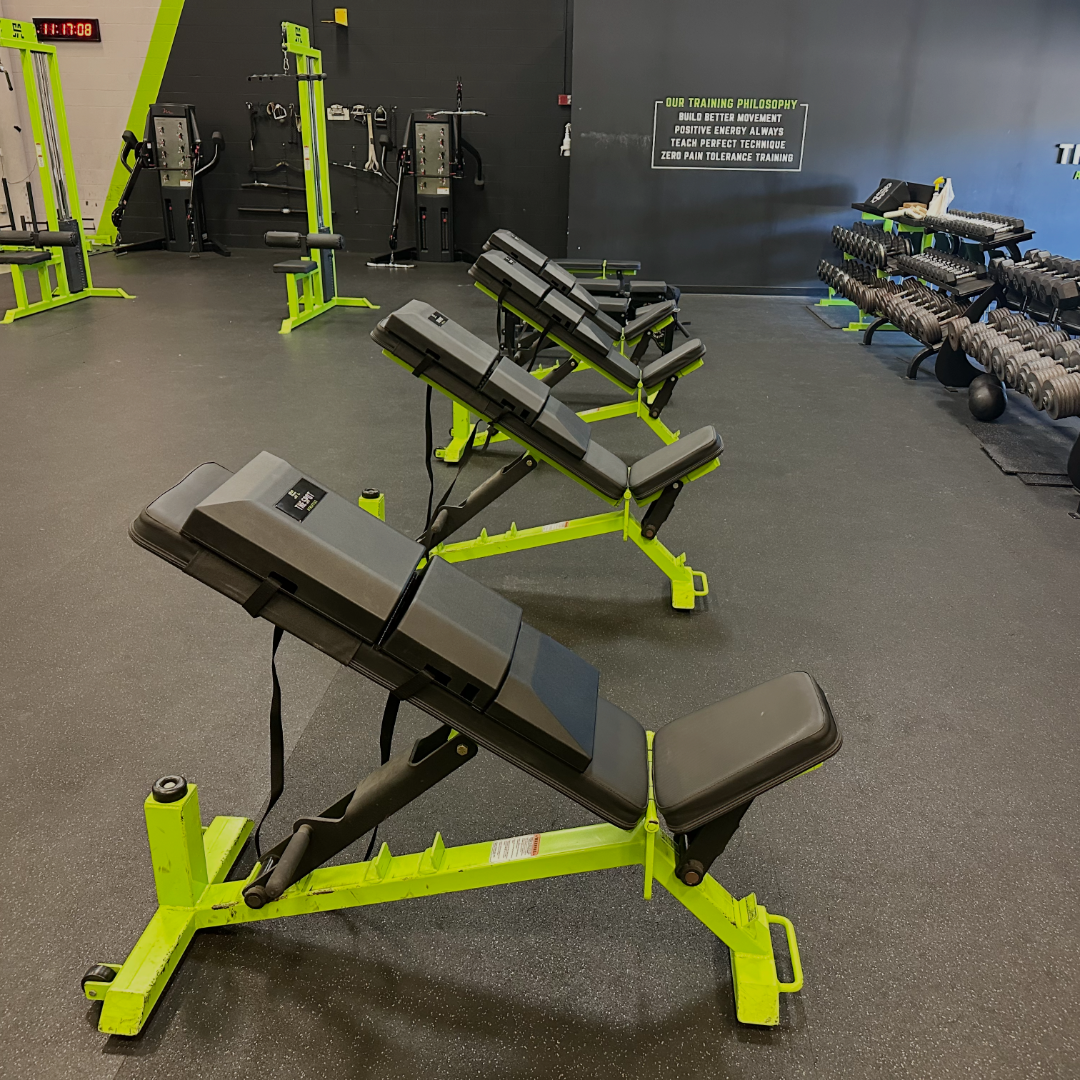 Four benches at The Spot Athletics featuring custom Launch Pads™ in front of the 'Training Philosophy' wall in a strength and conditioning facility.