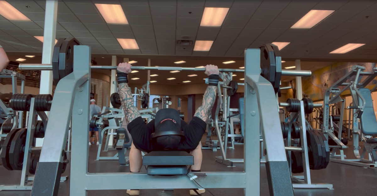 AMM archive photograph of a lifter pressing on a Launch Pad-equipped bench, seen from beyond the head of the bench.