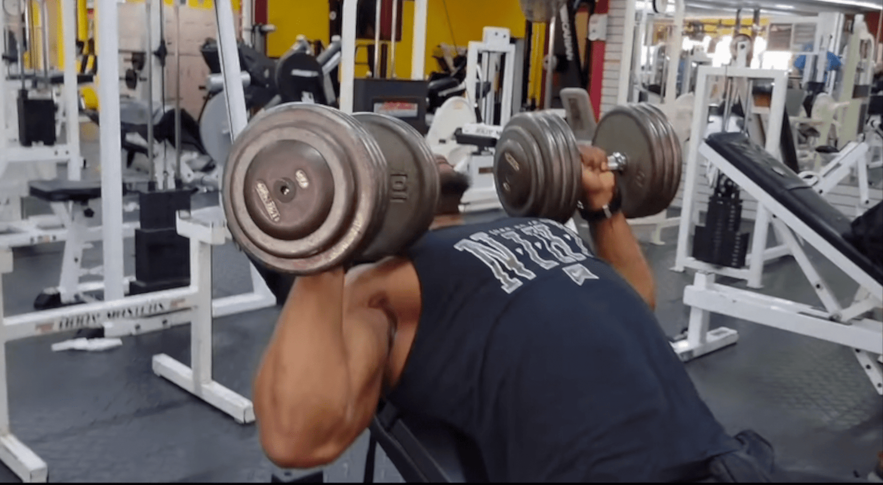 Athlete pressing two dumbbells while lying on The Launch Pad® in a gym.